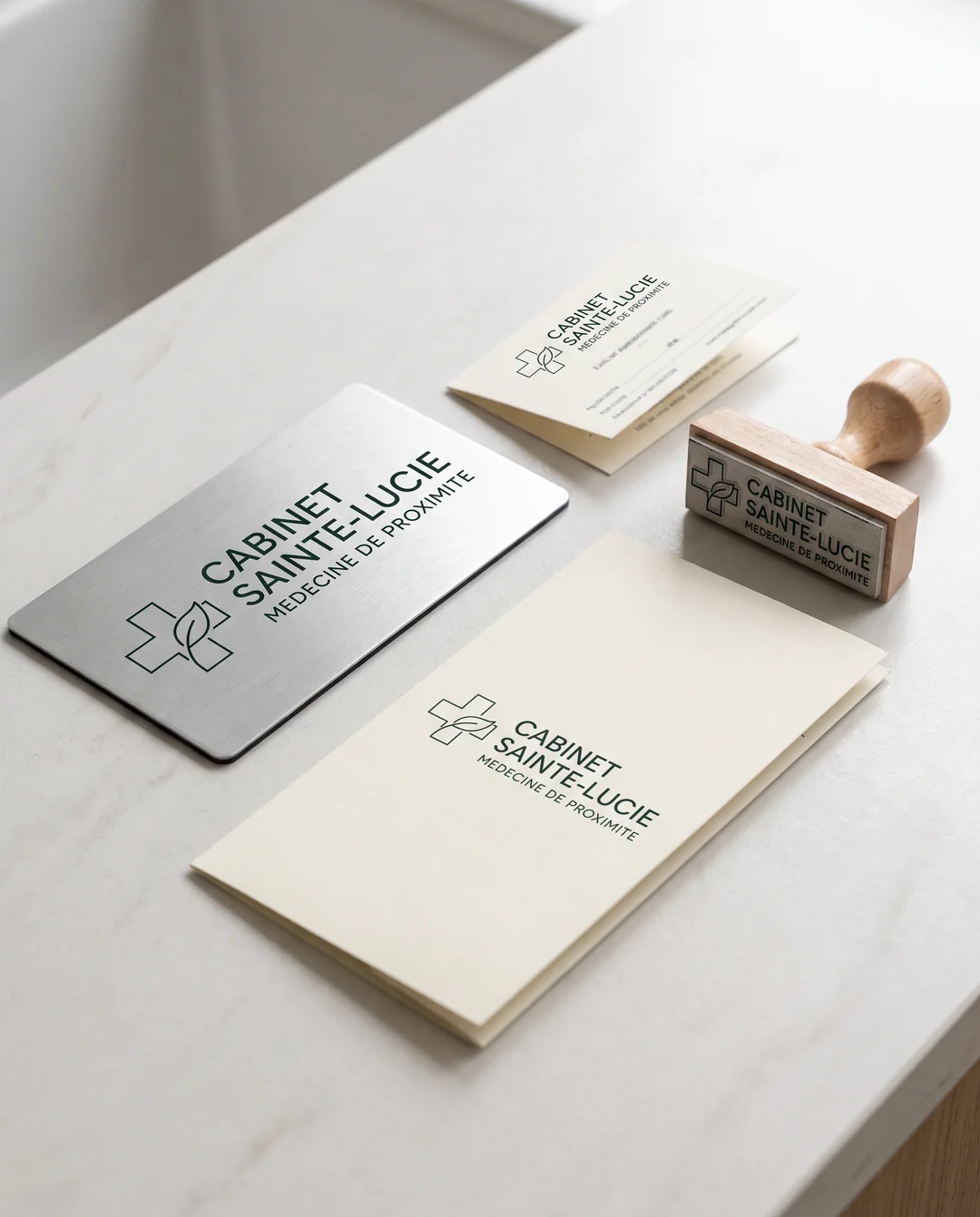 Planche d'identité Cabinet Sainte-Lucie : plaque de porte en métal brossé, carte de rendez-vous et tampon au même monogramme